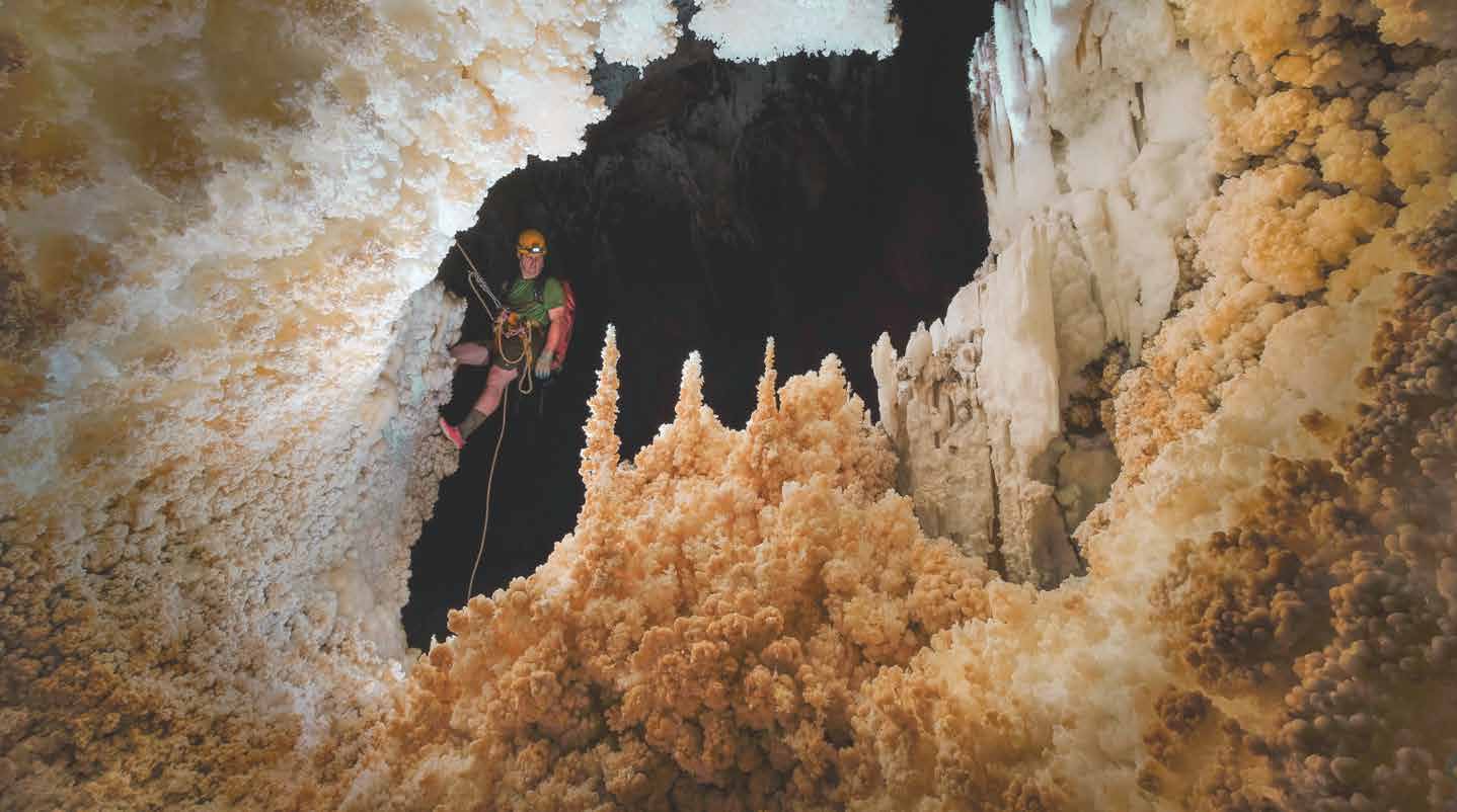 A caver rappelling into a limestone cave